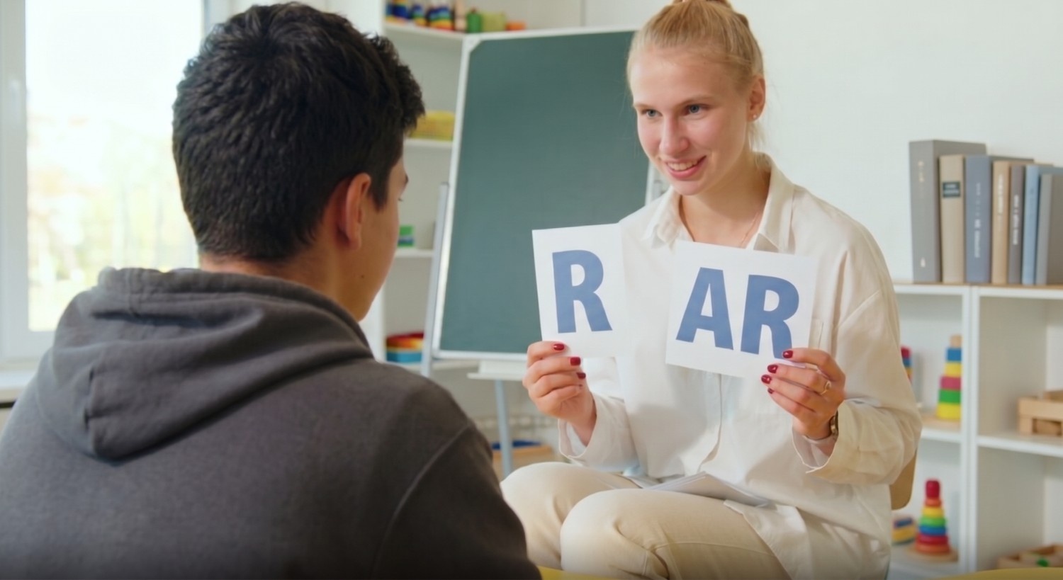Speech therapist working with a child on r sound articulation using picture cards